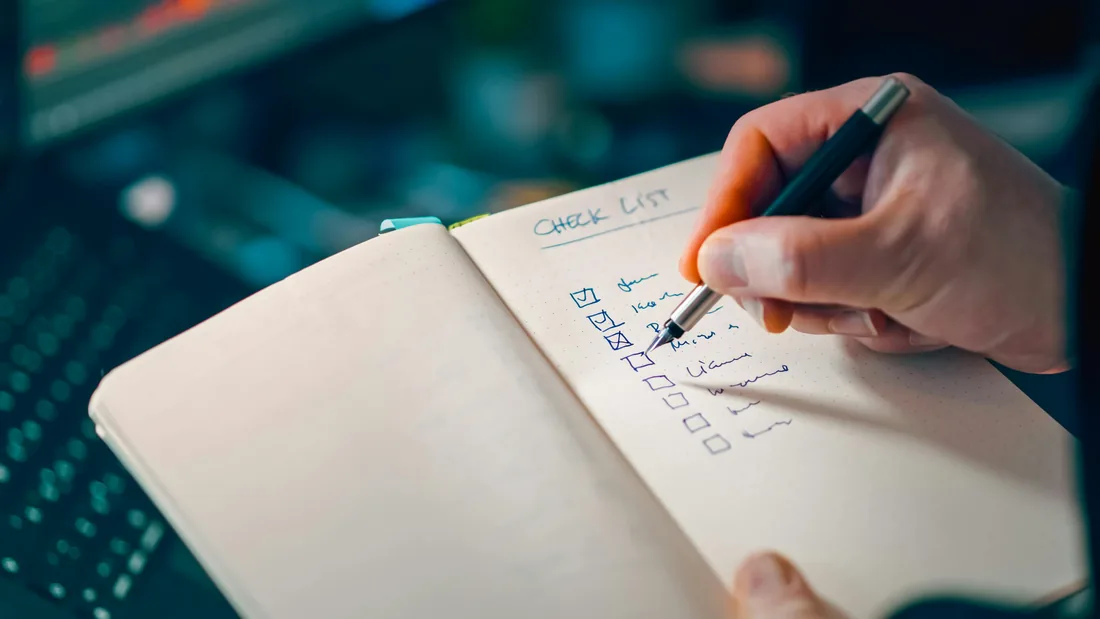 Mão a preencher uma checklist para organizar informação de uma página de prestador de serviços